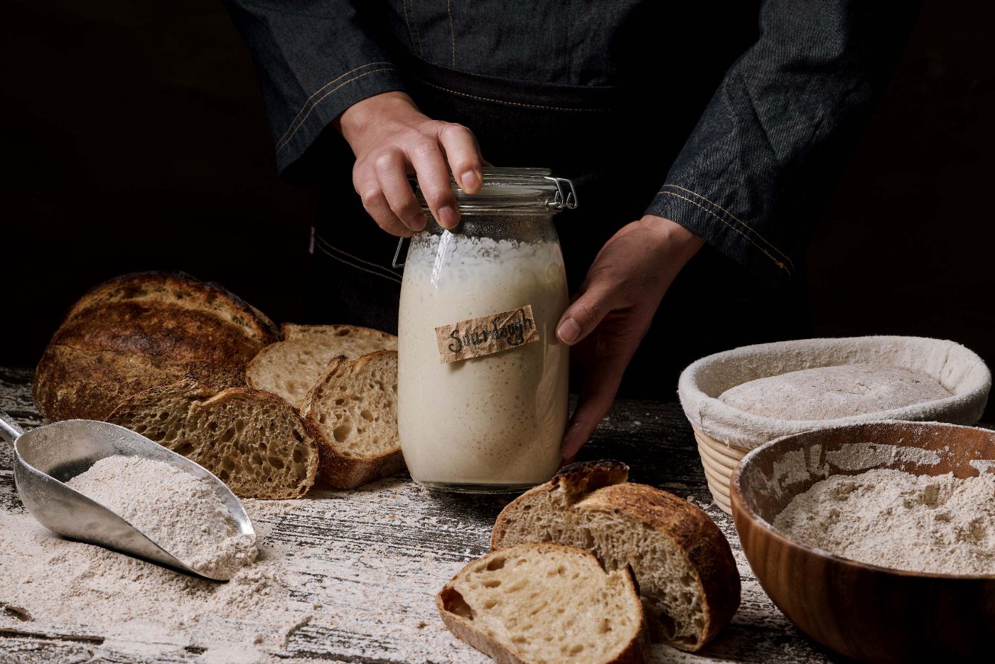 Jar of natural sourdough starter among fresh loaves